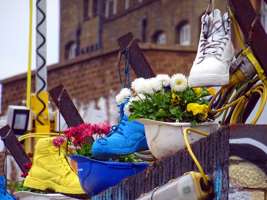 A collection of colorful floral arrangements featuring white daisies and yellow poinsettias in a white ceramic pot, complemented by vibrant yellow and blue sneakers, displayed on a weathered brick led